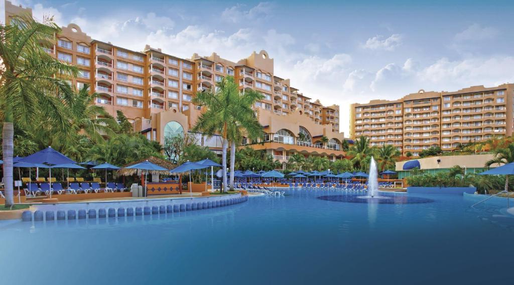 a resort with a large pool with chairs and umbrellas at Azul Ixtapa All Inclusive Resort in Ixtapa