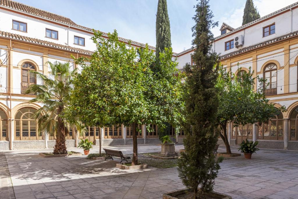 un patio con árboles frente a un edificio en Hotel Macià Monasterio de los Basilios, en Granada