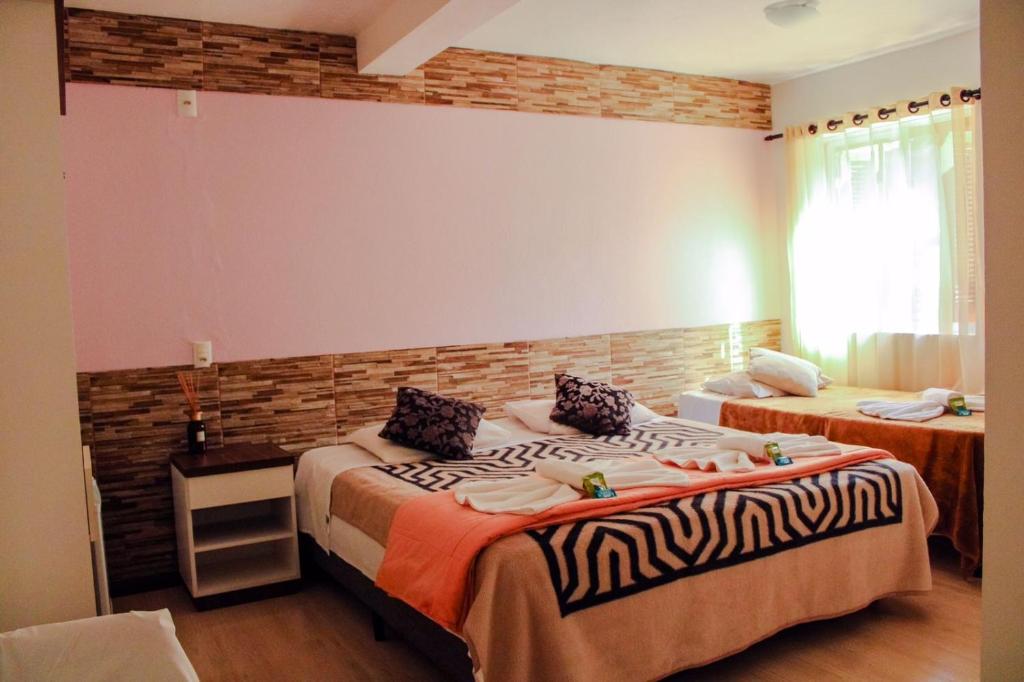Pousada Cantinho في غرامادو: غرفة نوم بسريرين وجدار من الطوب