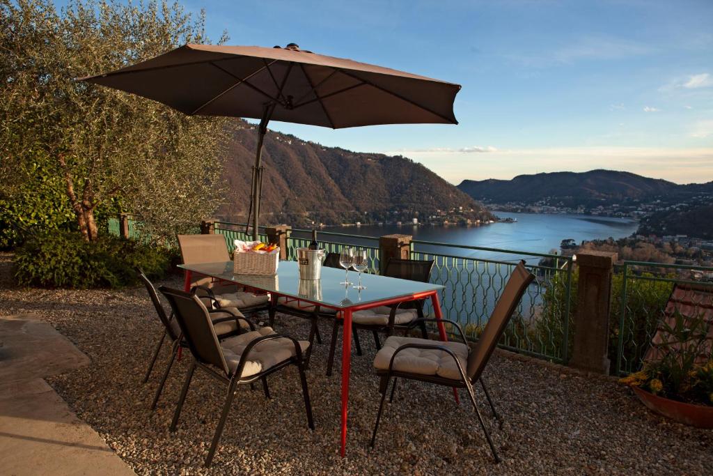 una mesa con sillas y una sombrilla en el balcón en Como Lake Panorama Apartment Sveva en Cernobbio