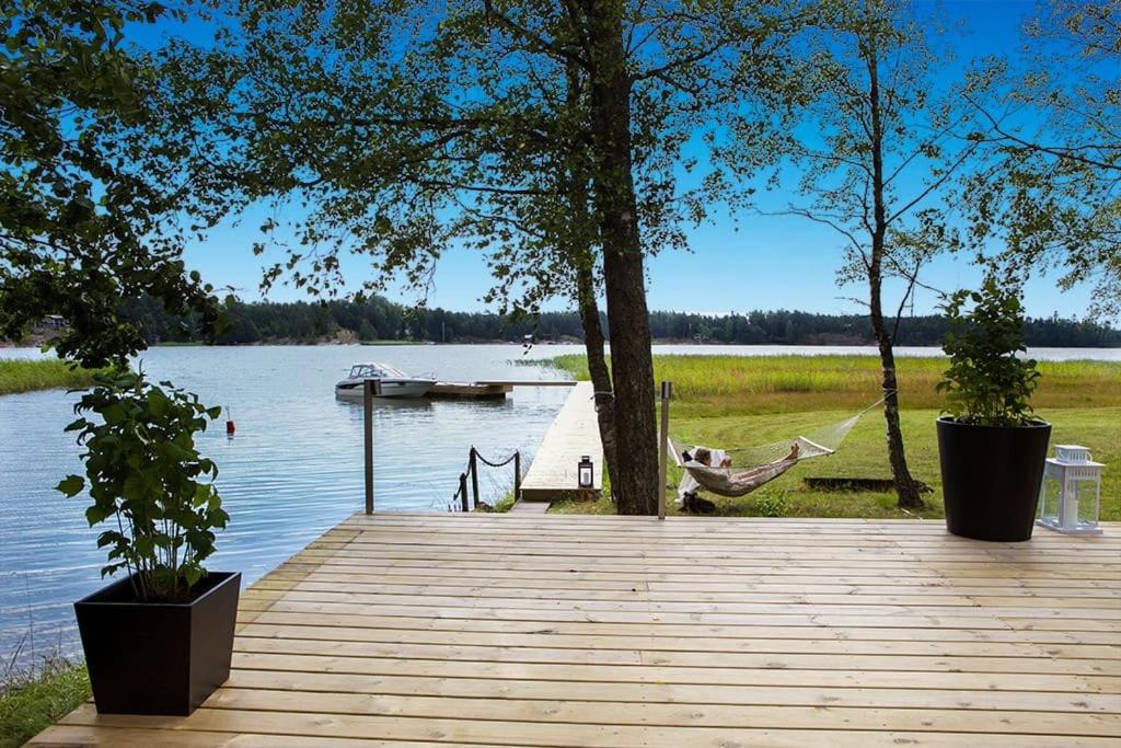 Ein Mann in einer Hängematte auf einem Dock neben einem See. in der Unterkunft Villa Dyyni - South Facing - Seafront - Jacuzzi in Helsinki