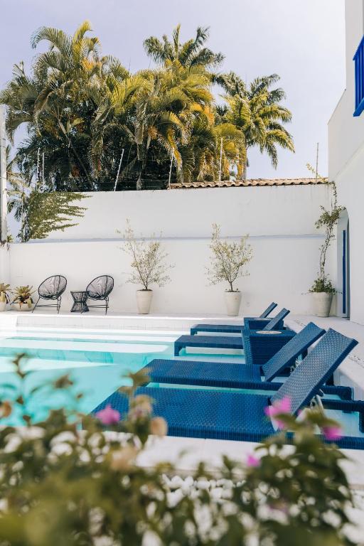 a pool with blue chairs and palm trees at Pousada Villa Santô in Guarujá
