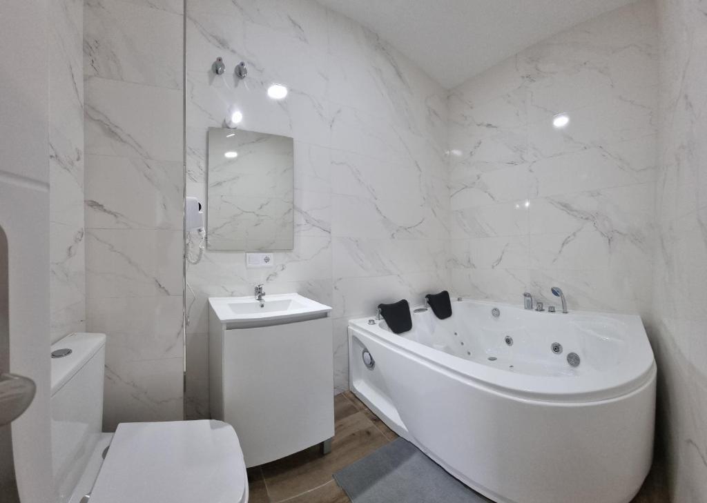 a white bathroom with a tub and a sink at Mini Estudio JACUZZI DOBLE SEVILLA "POLIGONO INDUSTRIAL" in Seville