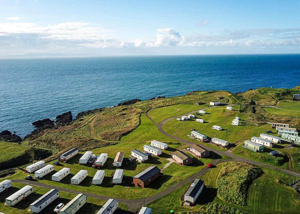 Burrowhead Holiday Village في Isle of Whithorn: اطلالة جوية على مزرعة بالقرب من المحيط