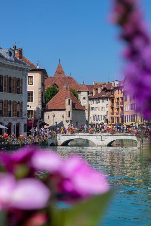 most nad rzeką w mieście z fioletowymi kwiatami w obiekcie La Résidence I Cœur vieille ville w Annecy