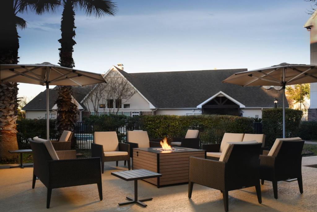 a patio with chairs and a fire pit with umbrellas at Residence Inn Houston Westchase On Westheimer in Houston