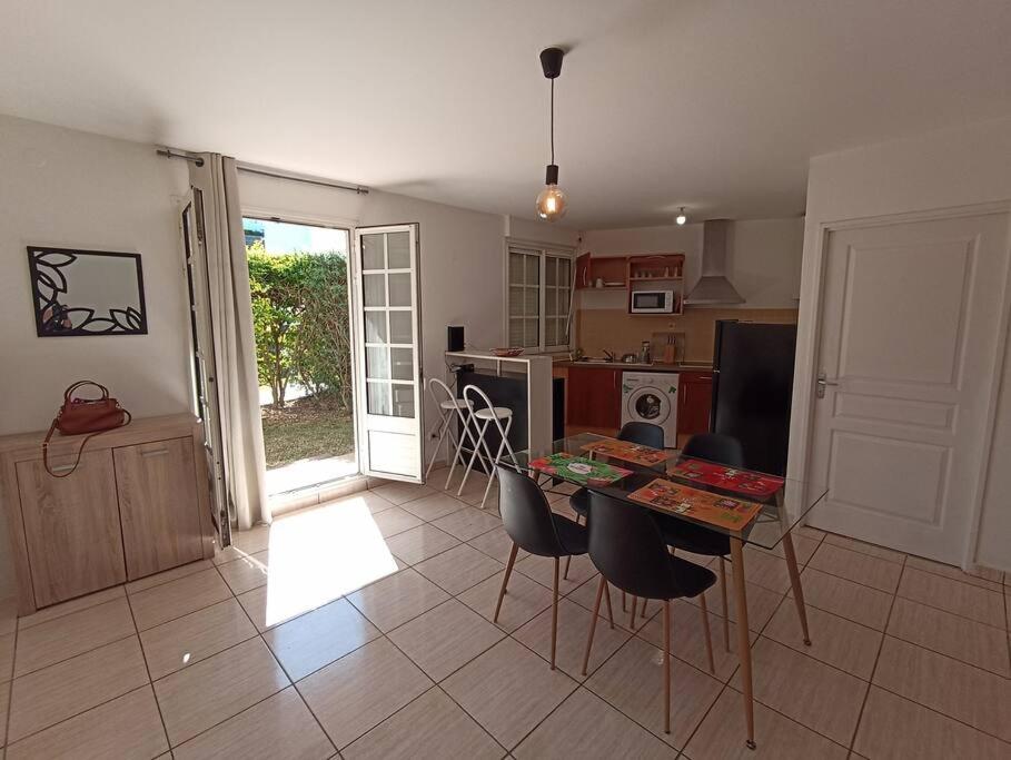 uma cozinha com mesa e cadeiras num quarto em Spacieux studio tout équipé em Le Tampon