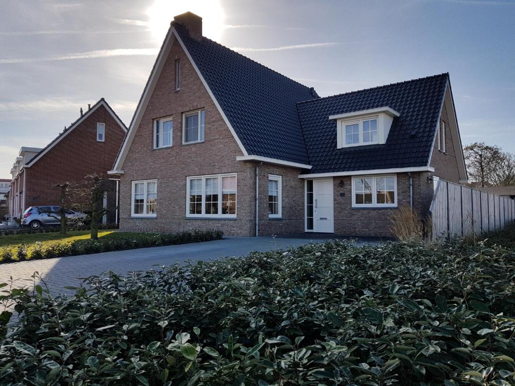 a brick house with a black roof at Luxe Kamer aan Zee in Zoutelande