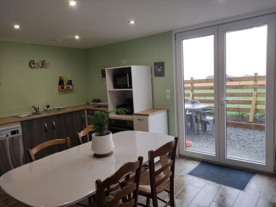 eine Küche mit einem Tisch mit Stühlen und einem Kühlschrank in der Unterkunft Le grand gîte d'Angélique en Normandie - 4 personnes in Norville
