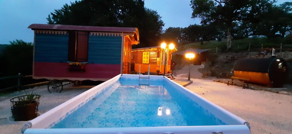 a swimming pool in front of a tiny house at Gite Roulottes de l' Alchimiste in Montjoie-en-Couserans