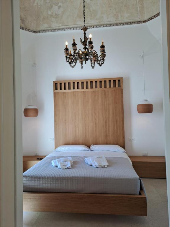 sypialnia z łóżkiem z żyrandolem w obiekcie Palazzo AD 1892 - SUITES & SPA w mieście Ostuni