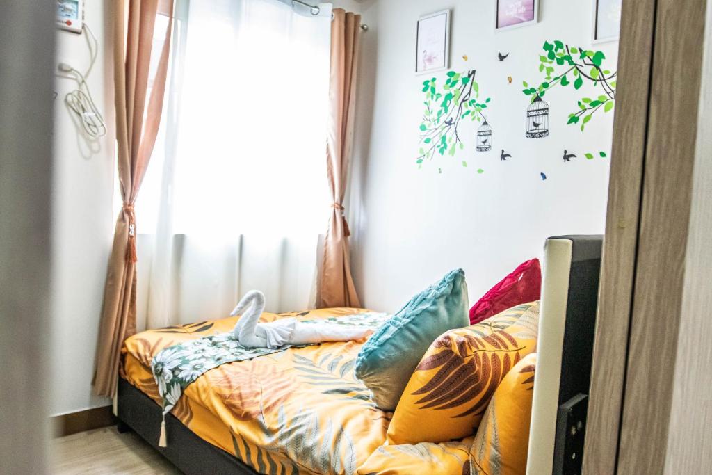 a bed with colorful pillows in a room with a window at Happy Hans Place in Trees Residences in Manila