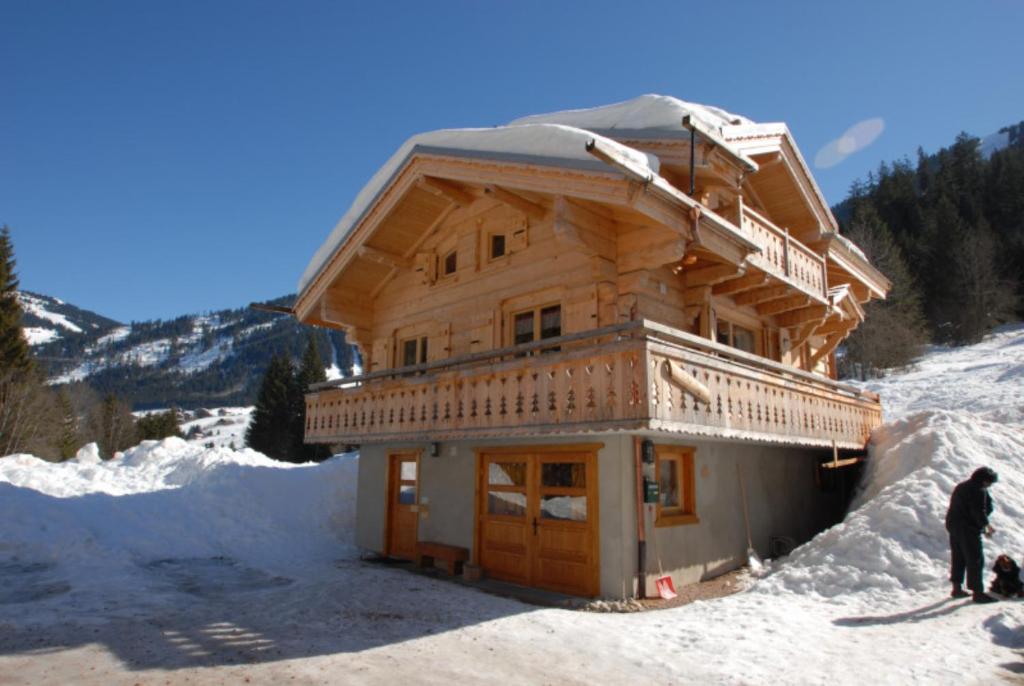 a log cabin in the snow with a man standing outside at Chalet Tho'max in Châtel
