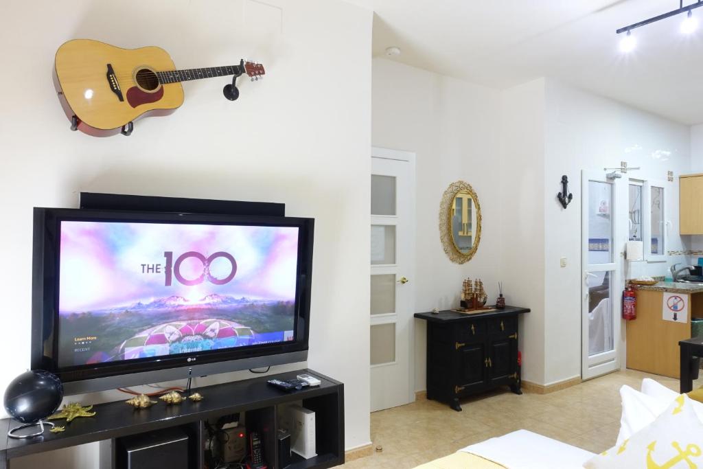 Una sala de estar con un televisor y una guitarra en la pared. en Best Valencia Beach Rooms-Shared Flat, en Valencia