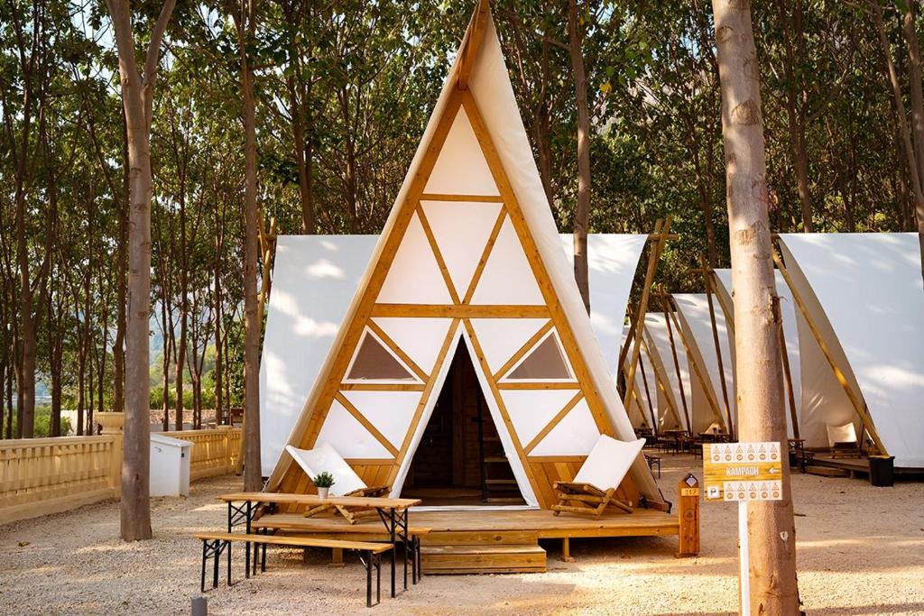 Tienda triangular con mesa y sillas frente a los árboles en Kampaoh Cova Negra, en Marxuquera (Marchuquera)