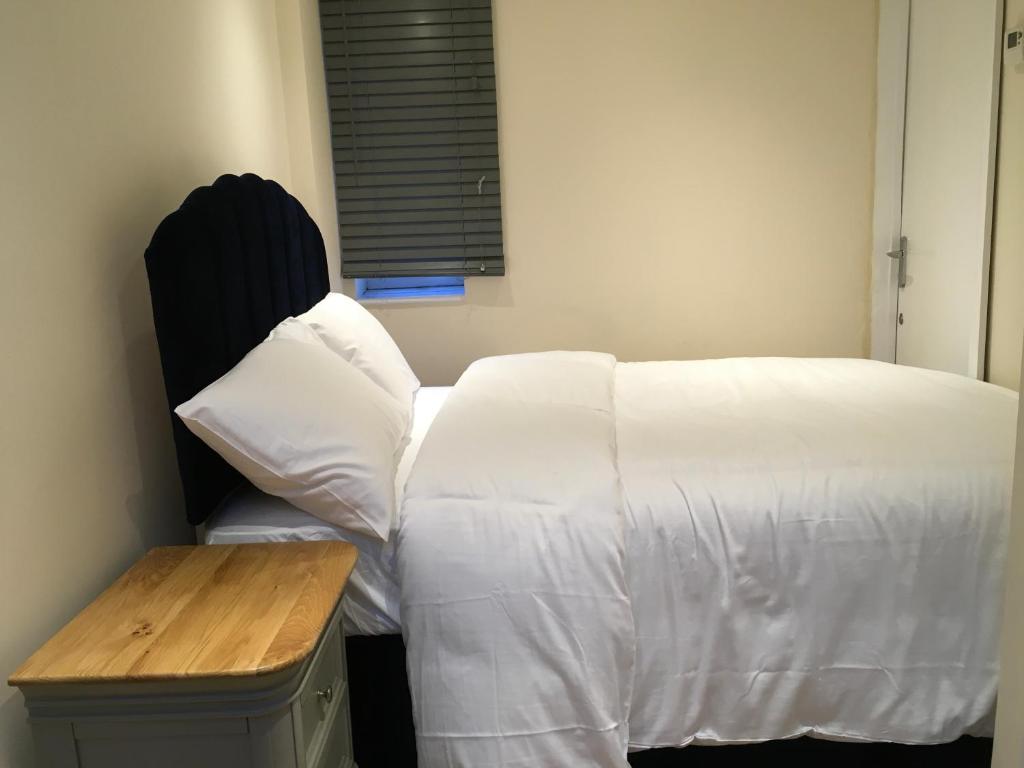 Schlafzimmer mit einem Bett mit weißer Bettwäsche und einem Tisch in der Unterkunft Private One Bedroom Apartment in Slades Green