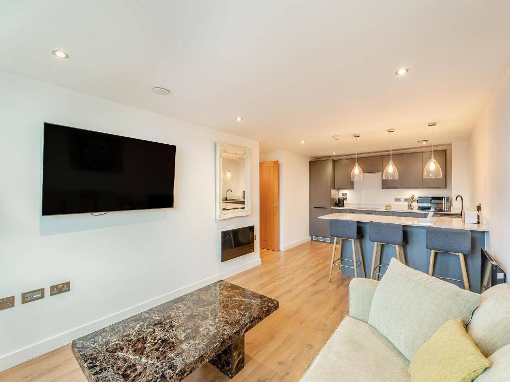 a living room with a couch and a tv on a wall at Queens Bridge Apartment in Ramsgate