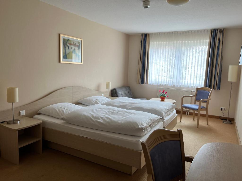 um quarto com uma grande cama branca e uma cadeira em Hotel am Stern Uelzen em Uelzen