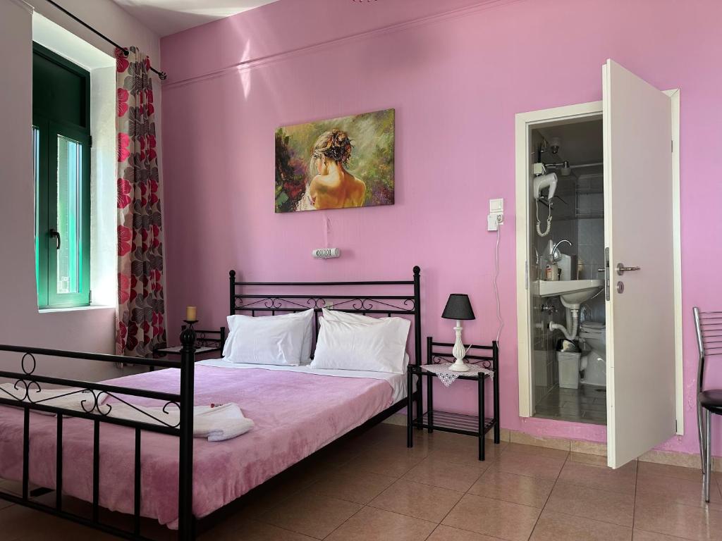 a bedroom with a bed with a pink wall at Akteon Rooms in Agia Galini