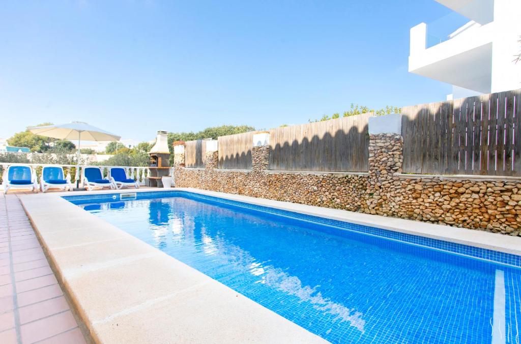 a swimming pool with chairs next to a wall at Villa Asarel by Sonne Villas in Cala Galdana