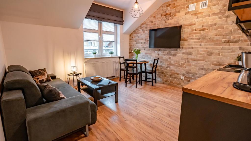 a living room with a couch and a brick wall at Centrum Cicha, Sun & Snow in Krynica Zdrój