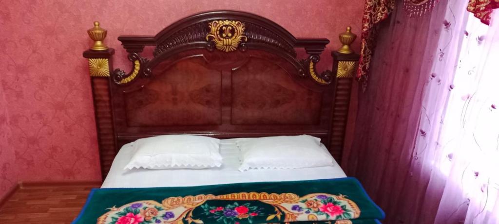 un letto con testiera in legno in una stanza di Уютная 3-х комнатная квартира в Хромтау a Khromtaū