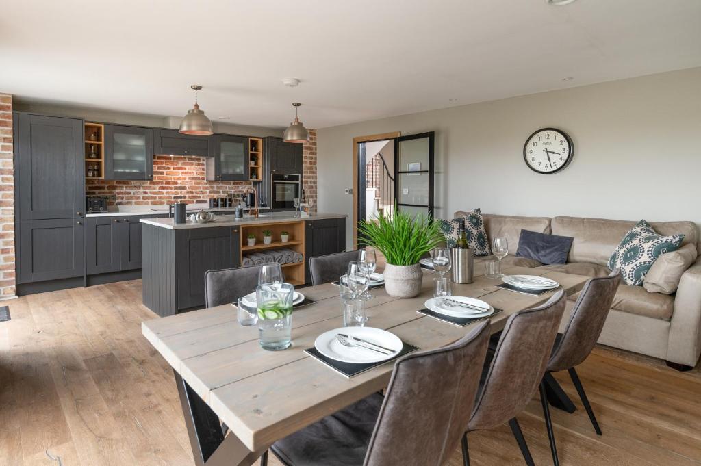 a kitchen and dining room with a wooden table and chairs at Designer Cotswold post house with external sauna in Tetbury