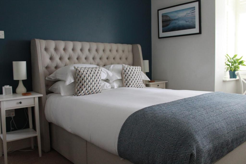 a bedroom with a large white bed with a blue wall at The Bosham Boathouse in Chichester