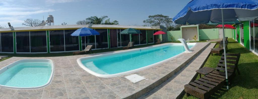 a swimming pool with an umbrella next to a building at Velaria in Chachalacas