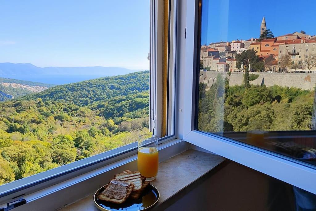 una ventana con un plato de comida y un vaso de zumo de naranja en The View, en Labin