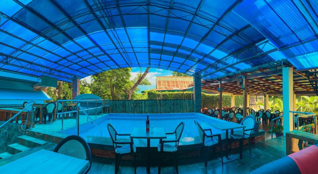 Mabini Hotel في مامباجاو: مسبح بالطاولات والكراسي وسقف ازرق