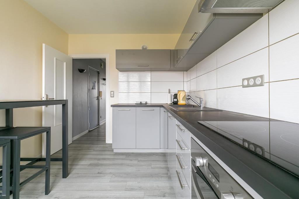 une cuisine avec des armoires blanches et un comptoir noir dans l'établissement LE TERROIR, au calme à deux pas du centre ville, à Dijon