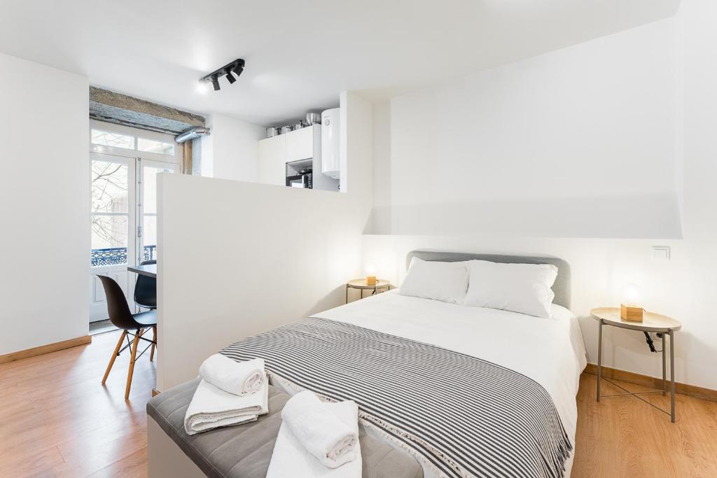 a white bedroom with a bed and a chair at Coreto Garden in Vila do Conde