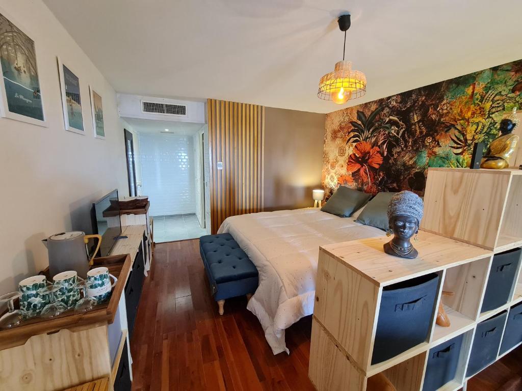 サンタンヌにあるAppartement Bilimbi Guadeloupe entre Sainte-Anne et Saint-Françoisのベッドルーム1室(ベッド1台付)が備わります。壁には絵画が飾られています。