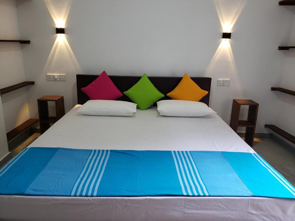 a bedroom with a bed with colorful pillows on it at Vaas Place in Hikkaduwa