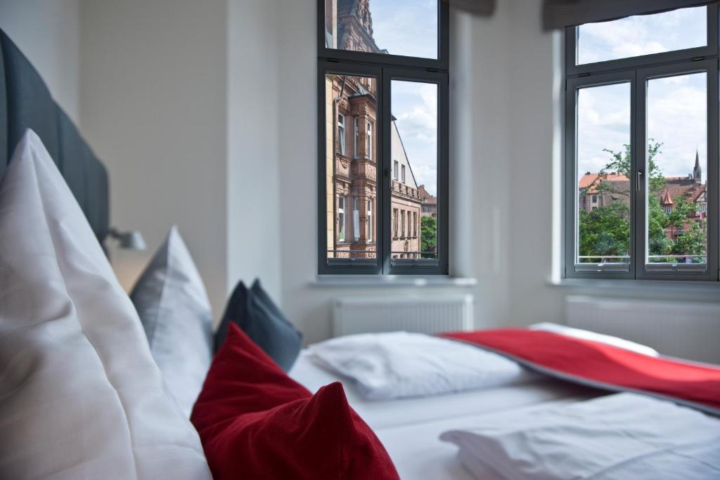 a bedroom with two beds and two windows at Gideon Hotel in Nürnberg