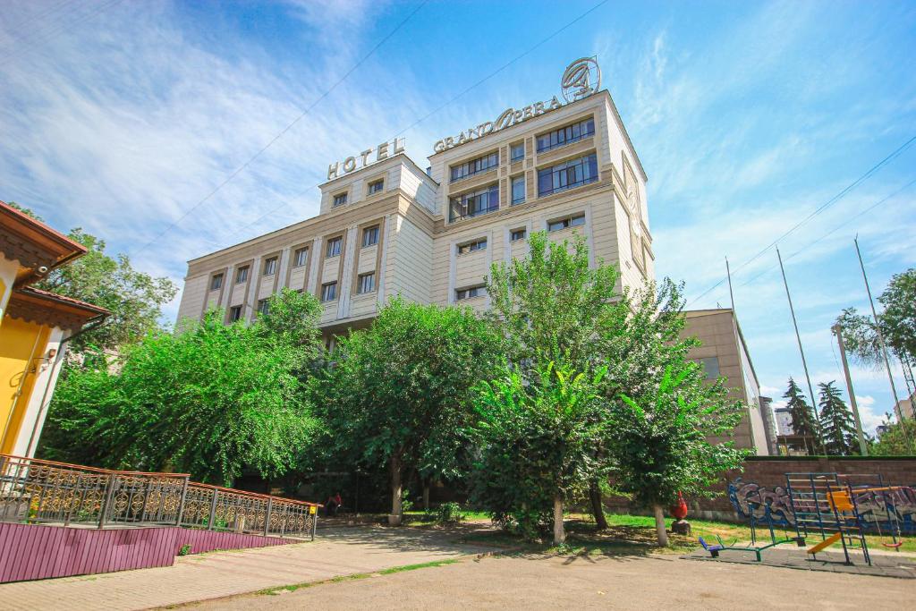 a large white building with trees in front of it at GRAND OPERA HOTEL in Almaty