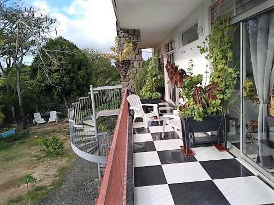 - une terrasse couverte avec un sol en damier dans une maison dans l'établissement Jolie studette dans un environnement arboré, à Les Abymes