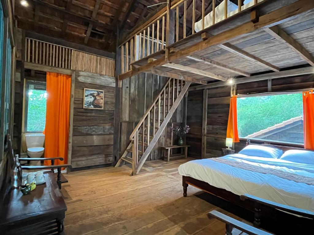 un dormitorio en el ático con una cama y una escalera en Boong House, en Bao Loc