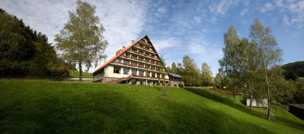 duży budynek na szczycie bujnego zielonego pola w obiekcie Hotel Rusava w mieście Rusava