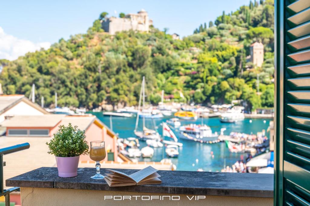 un bicchiere di vino e un libro su un tavolo con un porto di Casa Cristina by PortofinoVip a Portofino