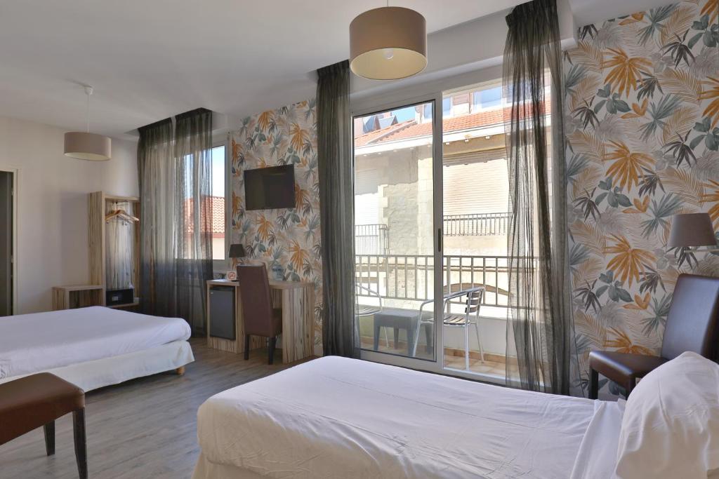 a hotel room with two beds and a balcony at Brit Hotel Marbella in Biarritz