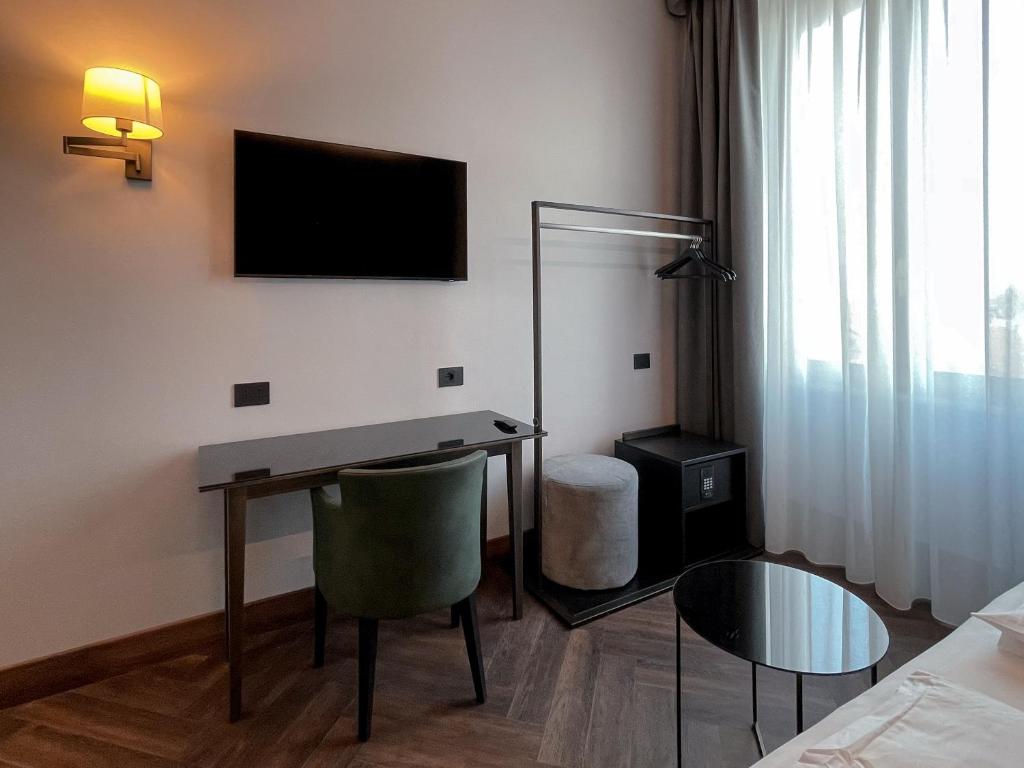 a hotel room with a desk and a television on the wall at Hotel Impero in Cremona