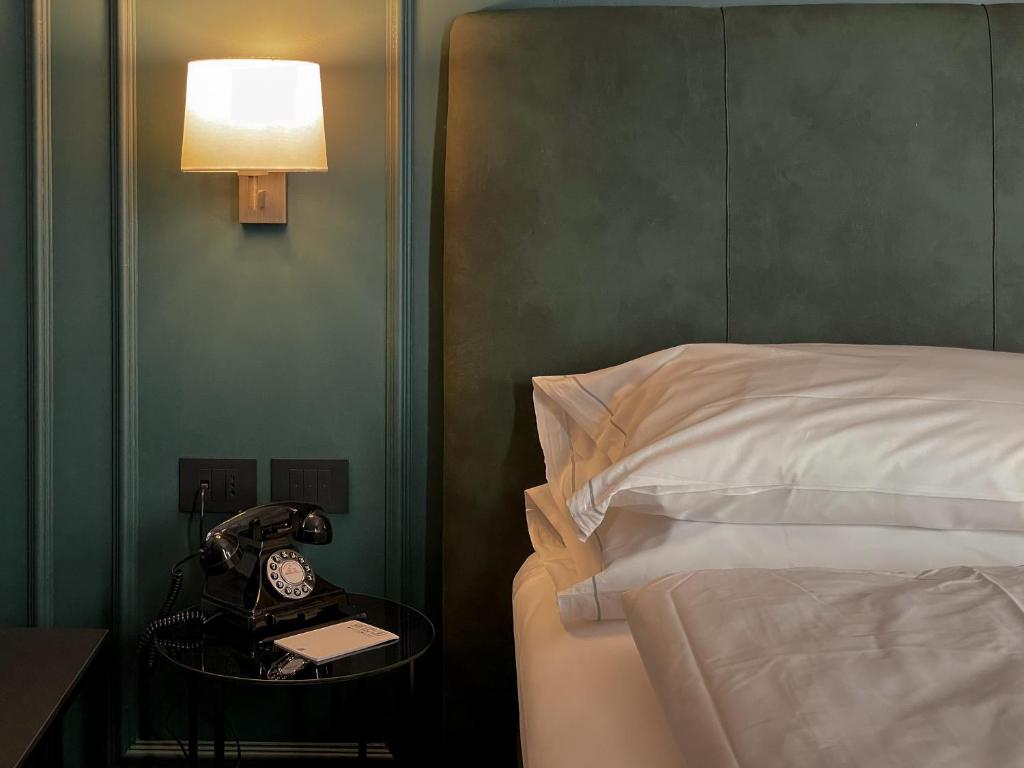 a hotel room with a bed and a phone on a table at Hotel Impero in Cremona
