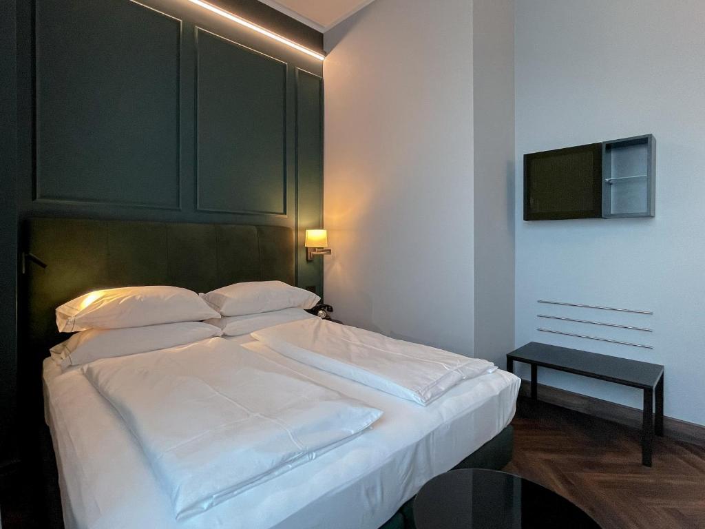 a bedroom with a large white bed and a table at Hotel Impero in Cremona