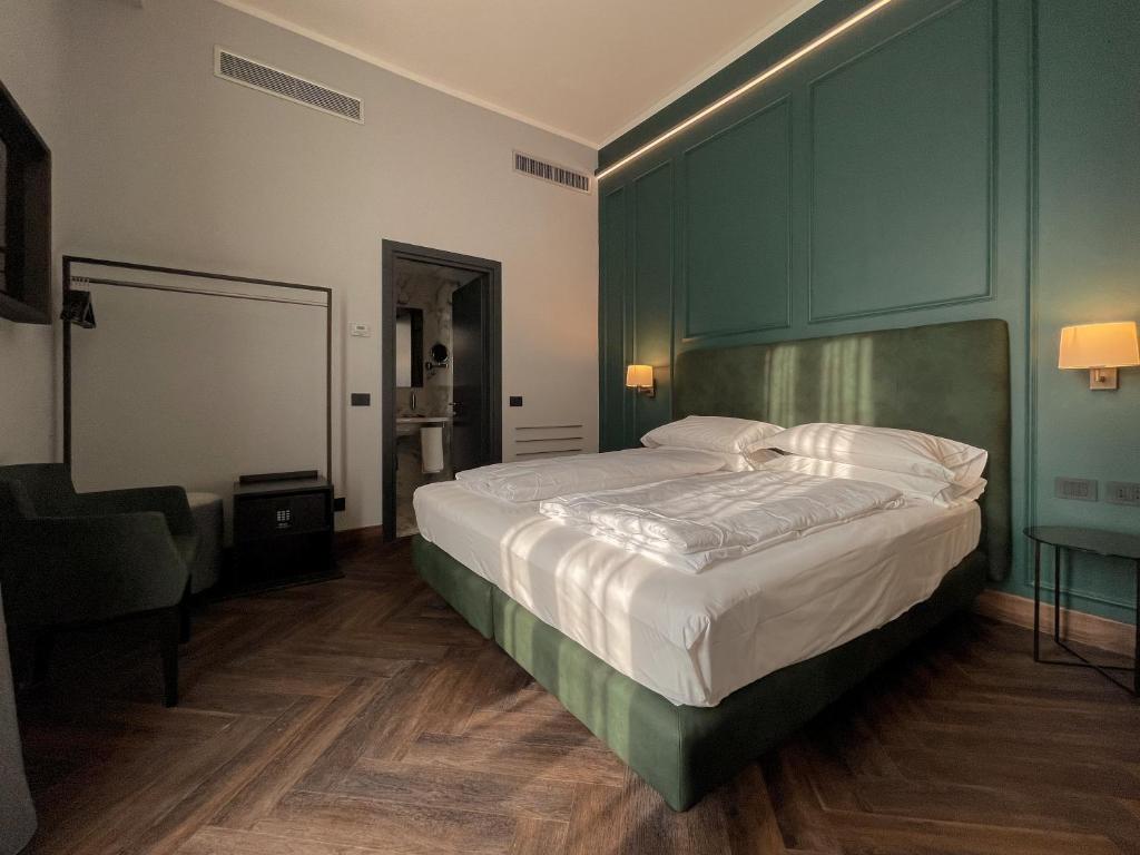 a bedroom with a large bed with a green headboard at Hotel Impero in Cremona