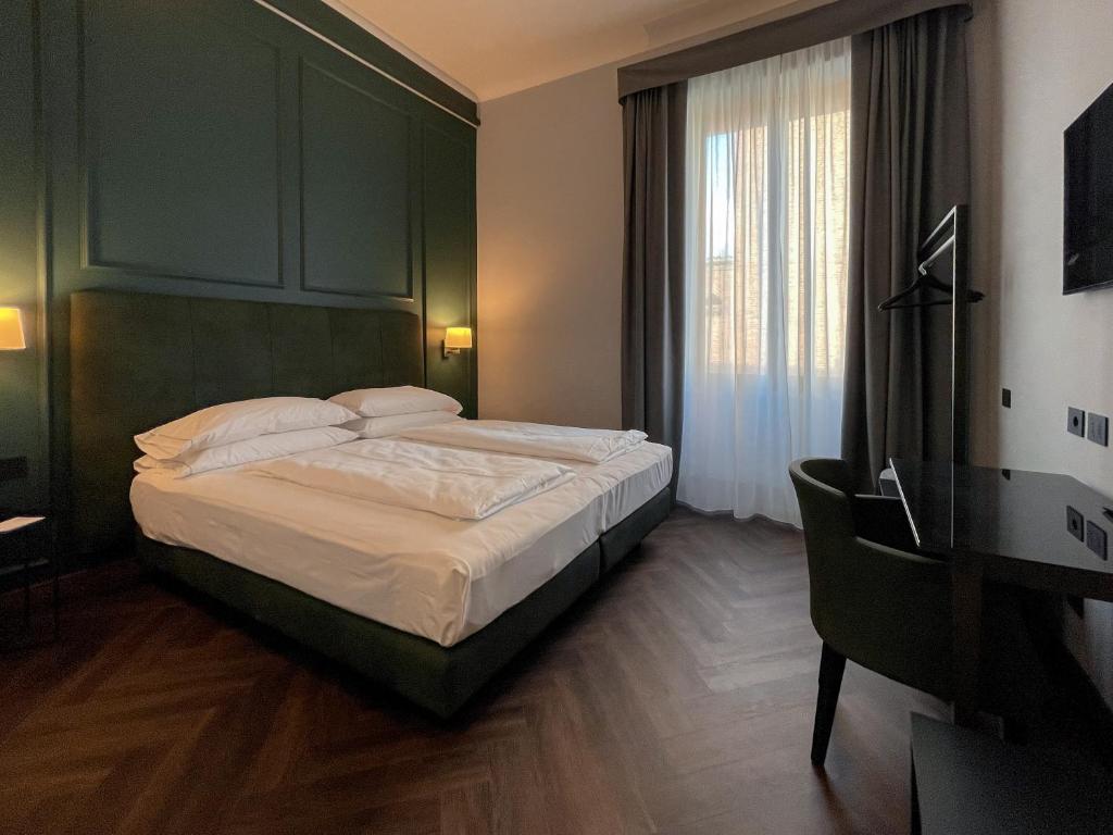 a bedroom with a large bed with a green headboard at Hotel Impero in Cremona