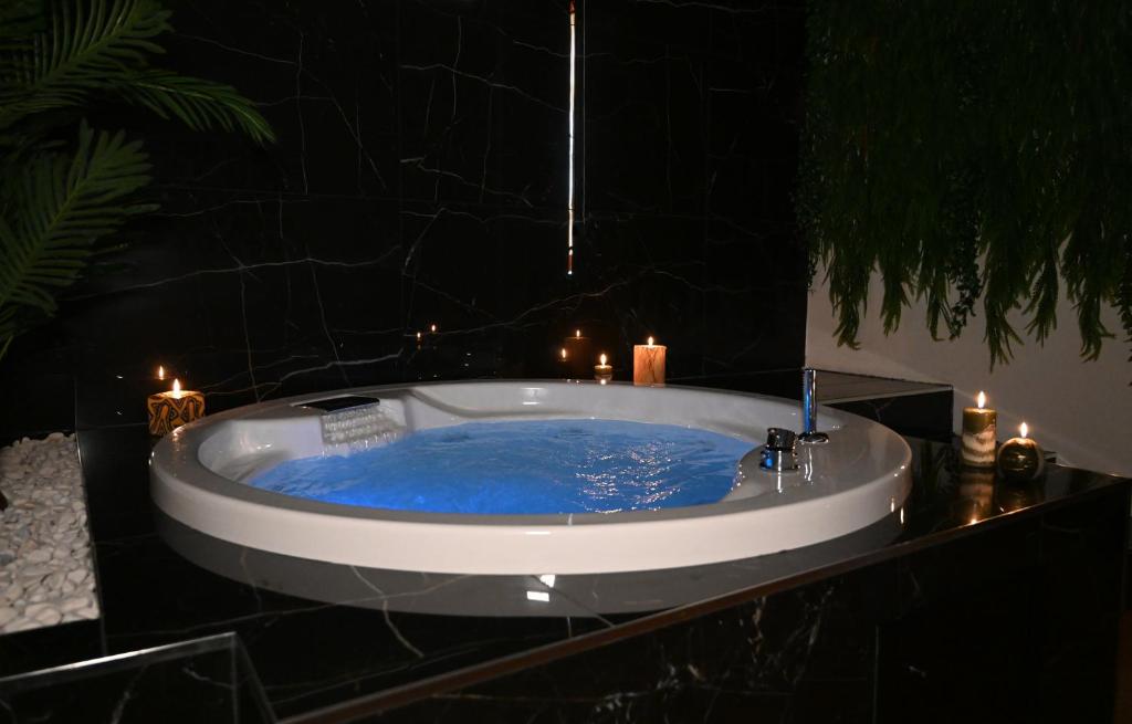 - une baignoire avec de l'eau bleue dans une chambre avec des bougies dans l'établissement Palace Eight - Suites & Spa, à Cosenza