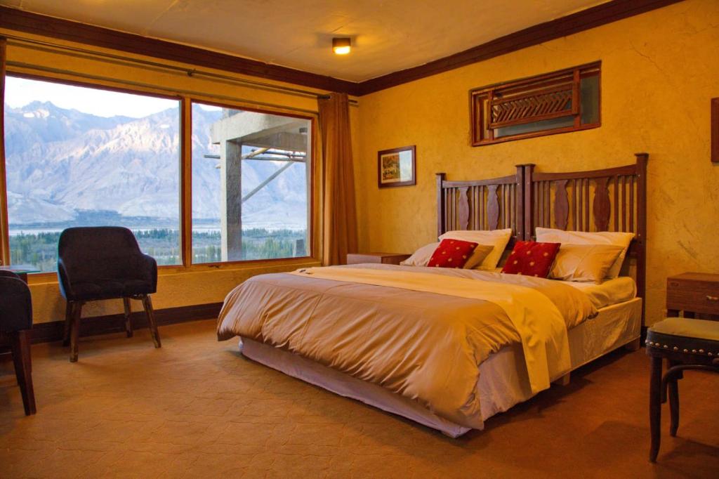 a bedroom with a large bed and a large window at Baltistan Fort Skardu Resort in Skardu