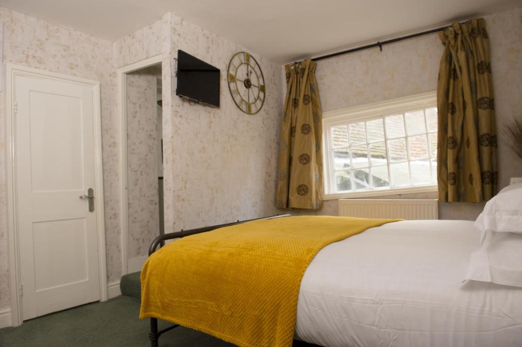 Un dormitorio con una cama con una manta amarilla. en The Sun Hotel en Canterbury